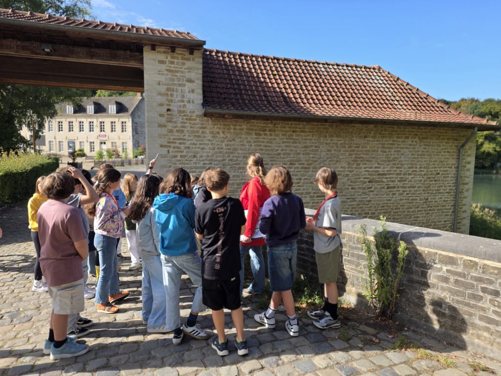 Un groupe d'élèves observant le mur du porche à l'entrée du site de Rouge-Cloître.