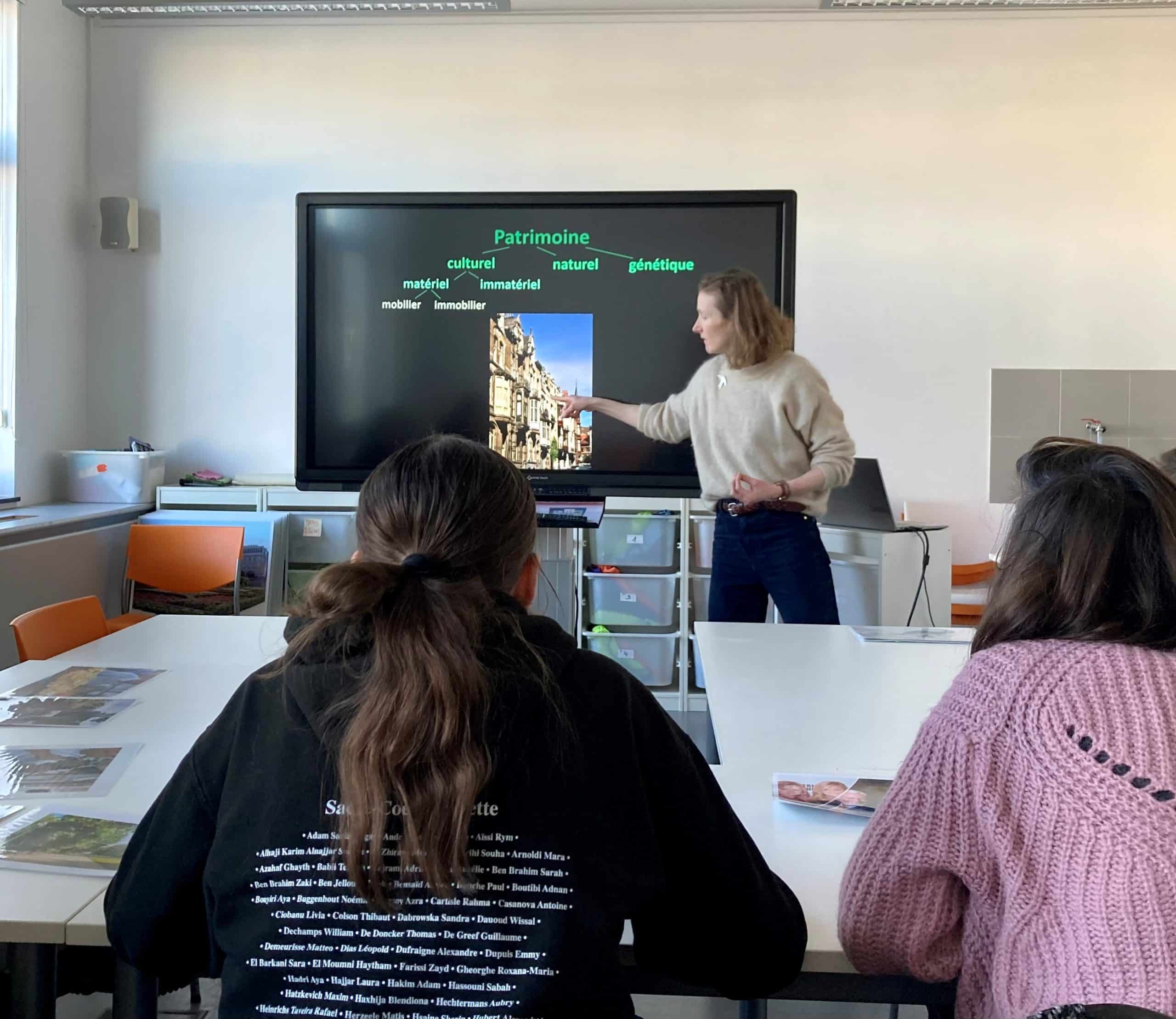une collaboratrice des Classes du Patrimoine montre une rue, une enfilade de façades sur l'écran d'un smartboard